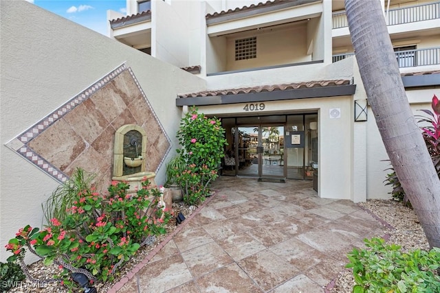 doorway to property featuring stucco siding, a garage, and a tile roof