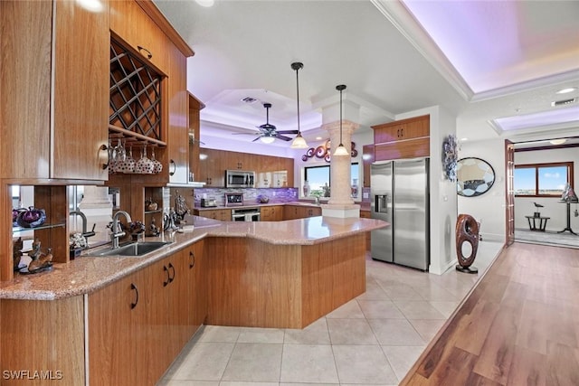 kitchen featuring a raised ceiling, sink, hanging light fixtures, kitchen peninsula, and stainless steel appliances