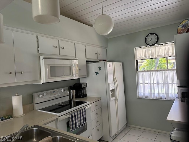 kitchen with white appliances, light tile patterned floors, white cabinets, light countertops, and a sink