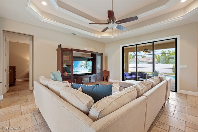 living room with ceiling fan, ornamental molding, and a tray ceiling