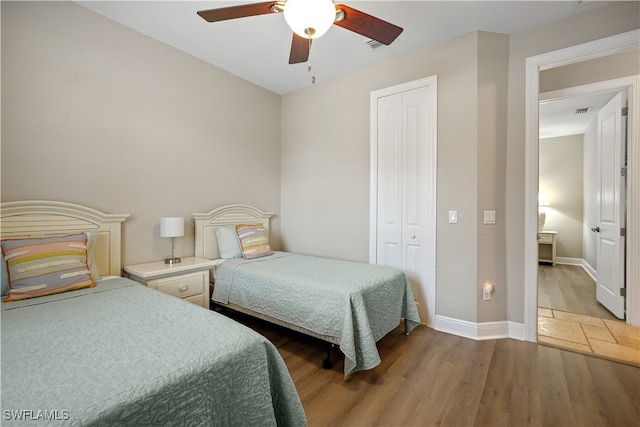 bedroom featuring dark wood-type flooring, a closet, and ceiling fan