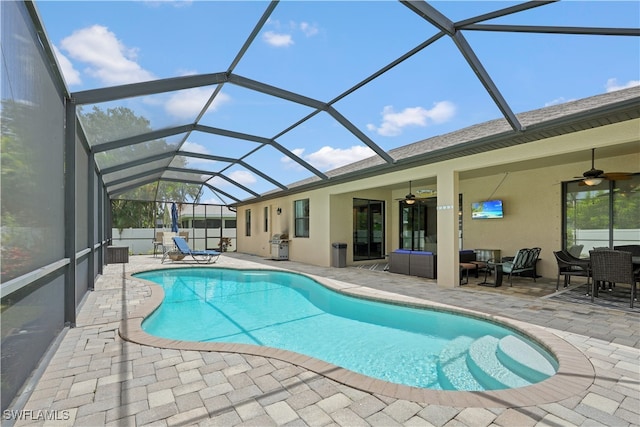 view of swimming pool featuring glass enclosure, ceiling fan, and a patio