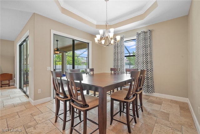 dining space featuring ceiling fan with notable chandelier, a tray ceiling, and ornamental molding