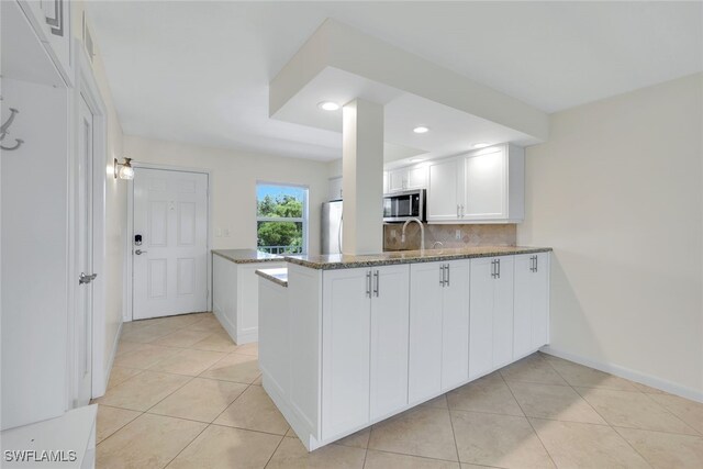 kitchen featuring white cabinetry, kitchen peninsula, light tile patterned floors, and tasteful backsplash