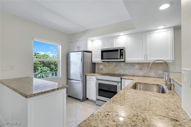 kitchen featuring light stone countertops, appliances with stainless steel finishes, tasteful backsplash, sink, and white cabinetry