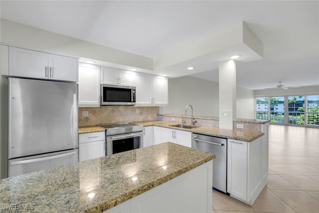 kitchen featuring light stone countertops, appliances with stainless steel finishes, sink, white cabinetry, and ceiling fan