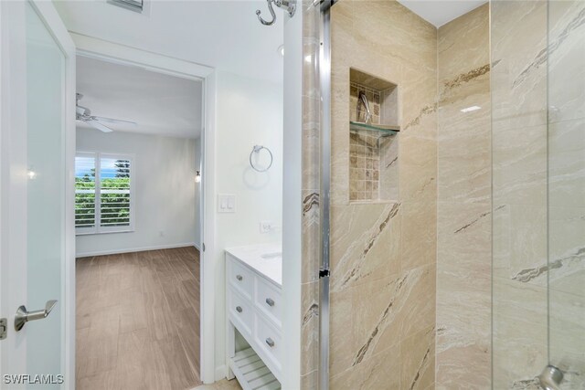 bathroom featuring tiled shower, vanity, ceiling fan, and hardwood / wood-style flooring