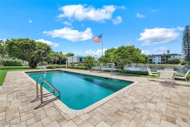 view of pool featuring a water view and a patio