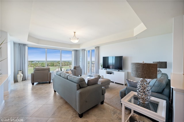 living room featuring a tray ceiling and light tile patterned floors