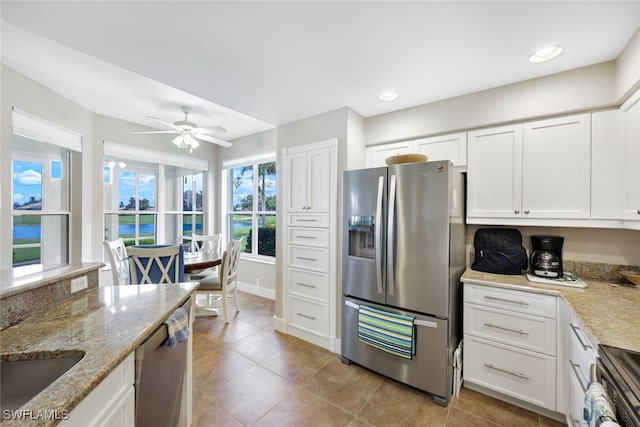 kitchen featuring light stone countertops, light tile patterned floors, stainless steel appliances, ceiling fan, and white cabinets