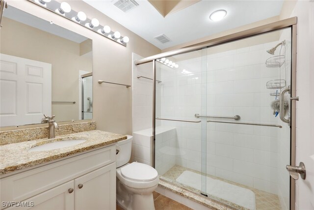 bathroom with vanity, toilet, tile patterned floors, and a shower with door