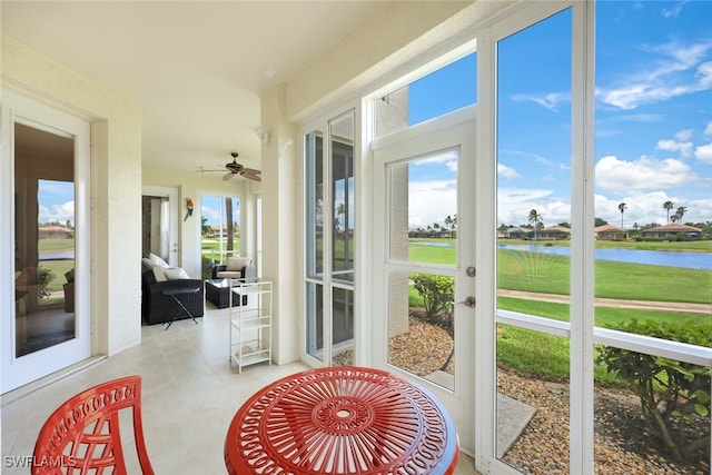 sunroom / solarium featuring a water view and ceiling fan