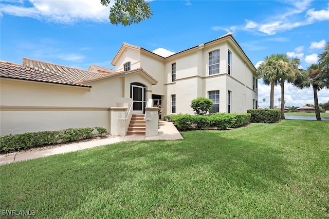 mediterranean / spanish-style house with a front yard, a tiled roof, and stucco siding