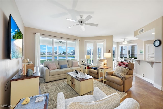 living area with light tile patterned floors, visible vents, baseboards, and ceiling fan