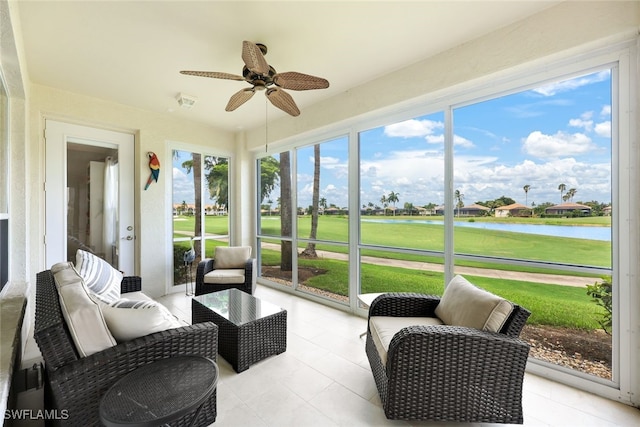 sunroom featuring a ceiling fan and a water view