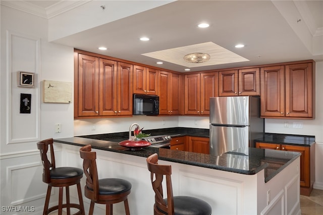 kitchen featuring a kitchen breakfast bar, dark stone countertops, crown molding, and stainless steel appliances