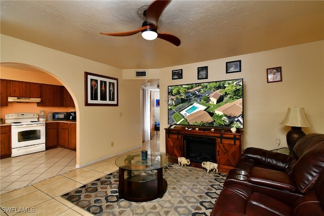 living room featuring a textured ceiling, ceiling fan, and light tile patterned flooring