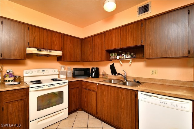 kitchen featuring sink, light tile patterned floors, and white appliances