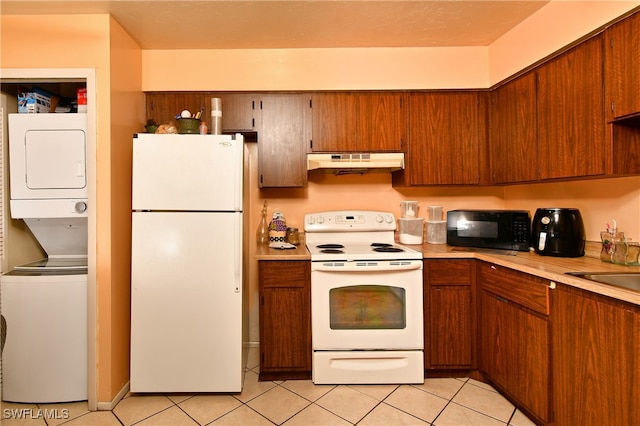 kitchen with white appliances, light tile patterned floors, and stacked washer and clothes dryer