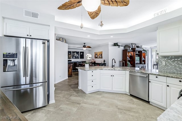 kitchen featuring white cabinets, ceiling fan, stainless steel appliances, and decorative backsplash