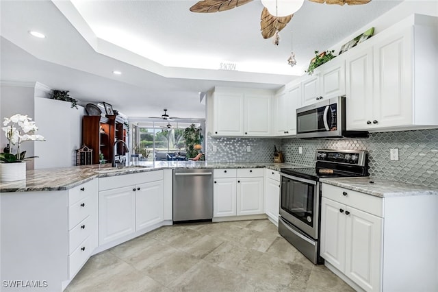 kitchen with appliances with stainless steel finishes, kitchen peninsula, sink, and ceiling fan