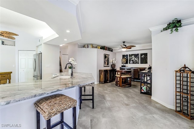 kitchen with stainless steel fridge, crown molding, kitchen peninsula, sink, and ceiling fan