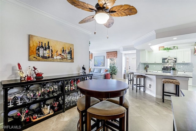 tiled dining space with ceiling fan, ornamental molding, and sink