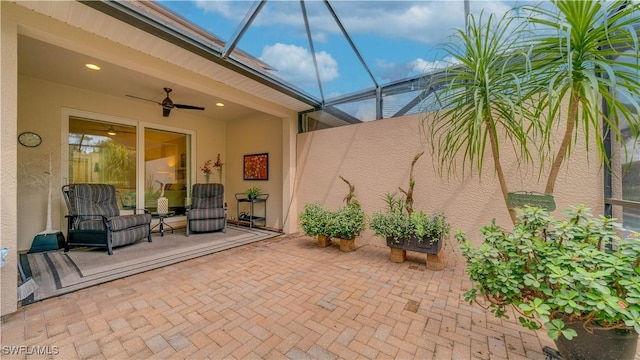 view of patio with ceiling fan and glass enclosure