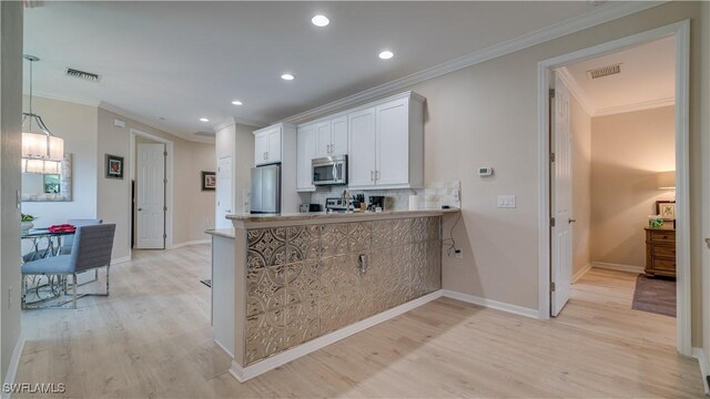 kitchen featuring light hardwood / wood-style floors, stainless steel appliances, backsplash, crown molding, and white cabinets