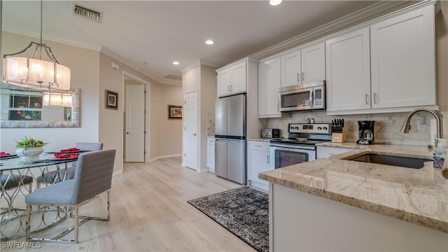 kitchen featuring appliances with stainless steel finishes, white cabinetry, a sink, and light stone counters