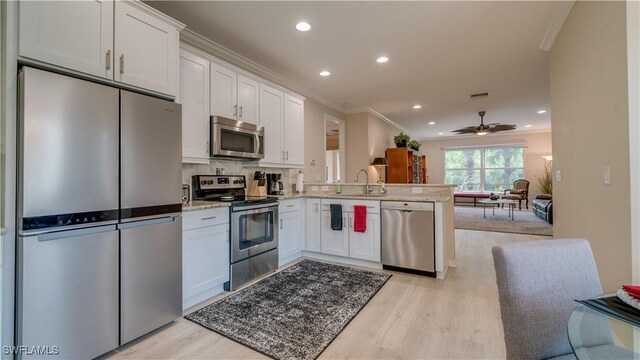 kitchen featuring white cabinets, stainless steel appliances, light hardwood / wood-style floors, sink, and kitchen peninsula