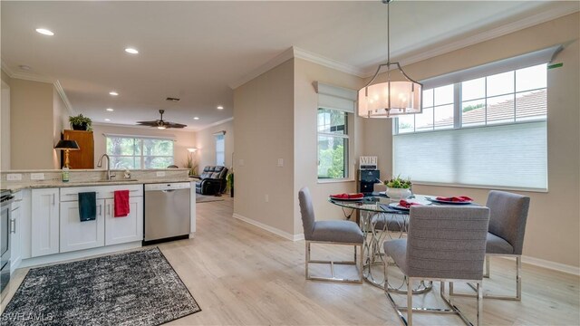 kitchen with white cabinetry, hanging light fixtures, stainless steel dishwasher, light hardwood / wood-style flooring, and sink