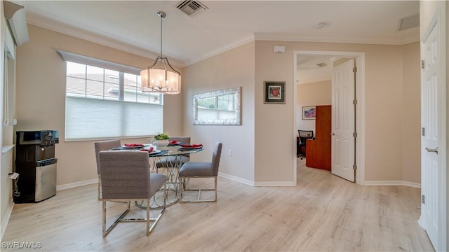 dining space with a notable chandelier, ornamental molding, and light hardwood / wood-style flooring