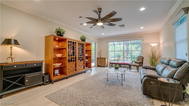 living room featuring light hardwood / wood-style floors, crown molding, and ceiling fan