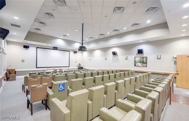 carpeted home theater room with a drop ceiling