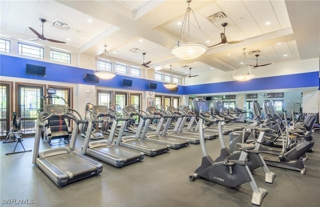 workout area featuring a towering ceiling and coffered ceiling