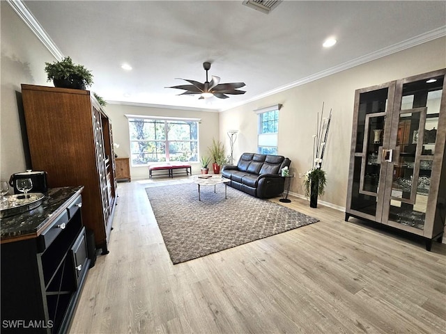 living area featuring light wood finished floors, visible vents, and ornamental molding