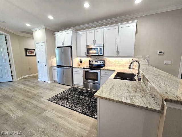 kitchen with white cabinets, light stone counters, stainless steel appliances, light wood-type flooring, and a sink