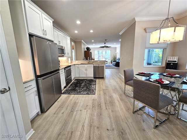 kitchen featuring pendant lighting, stainless steel appliances, light countertops, open floor plan, and a peninsula