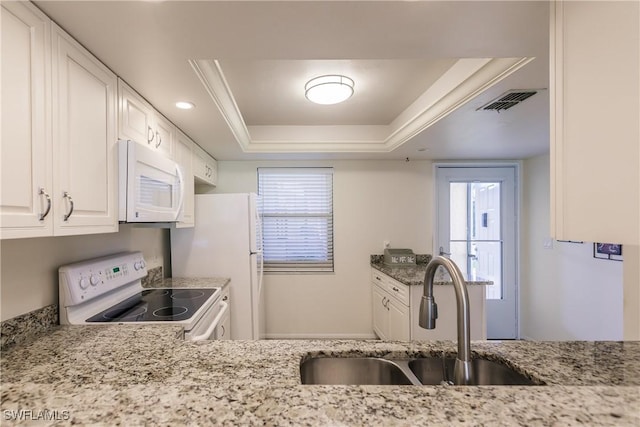 kitchen featuring light stone countertops, sink, white appliances, a tray ceiling, and white cabinets