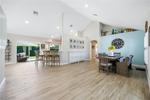 dining space featuring light wood-type flooring and high vaulted ceiling