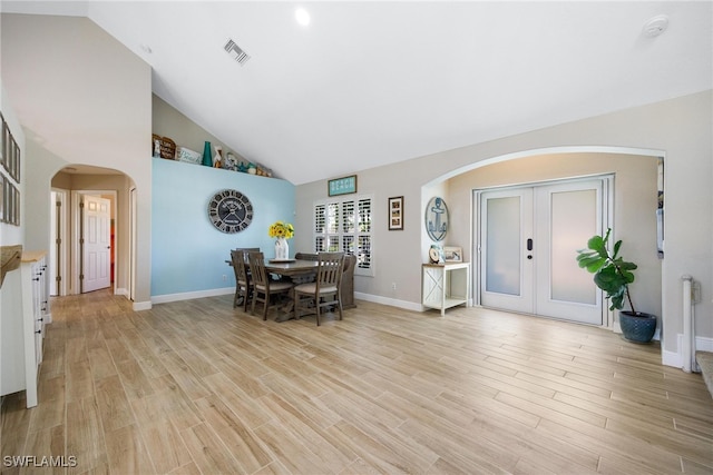 dining area with light wood-type flooring, high vaulted ceiling, and french doors