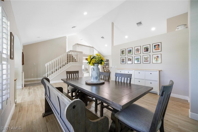 dining room with light wood-type flooring, high vaulted ceiling, and a healthy amount of sunlight