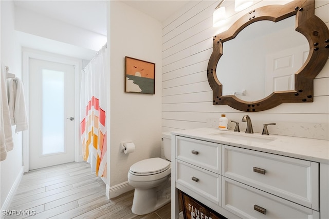 bathroom with hardwood / wood-style floors, vanity, toilet, and wooden walls