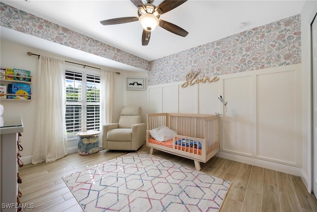 bedroom with ceiling fan, light hardwood / wood-style floors, and a crib