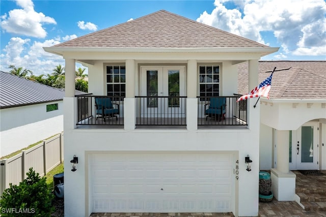 back of house featuring french doors, a balcony, and a garage