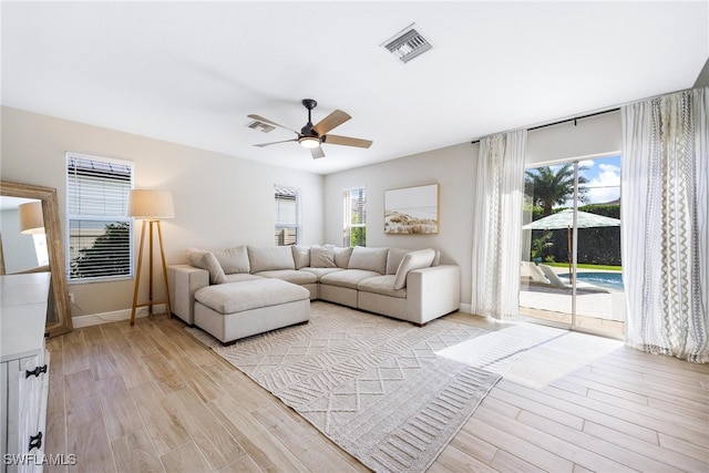 living room with ceiling fan, light wood-type flooring, and a wealth of natural light