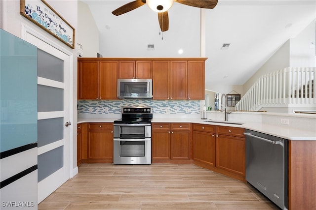 kitchen with high vaulted ceiling, sink, ceiling fan, decorative backsplash, and stainless steel appliances