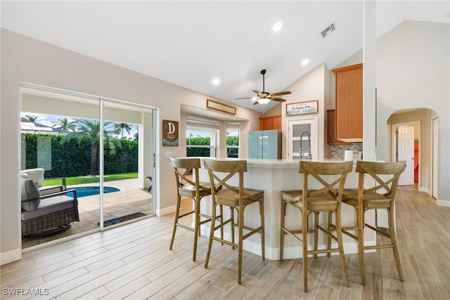 kitchen featuring stainless steel fridge, light hardwood / wood-style flooring, high vaulted ceiling, and a wealth of natural light