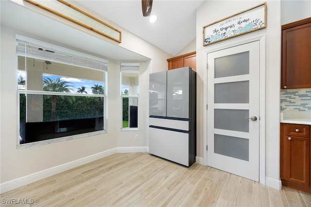 kitchen featuring ceiling fan, vaulted ceiling, tasteful backsplash, and light hardwood / wood-style flooring